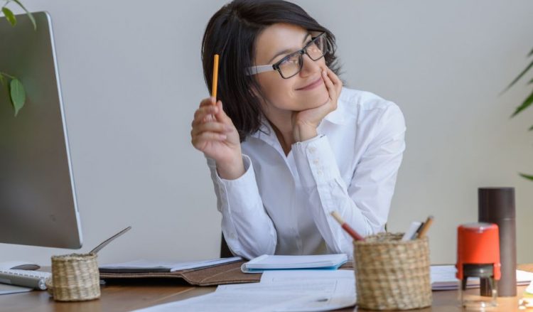 Happy woman thinking at her desk