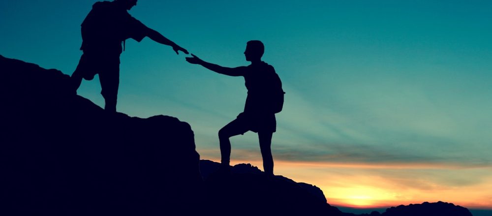 Climbers helping each other ascend a mountain.