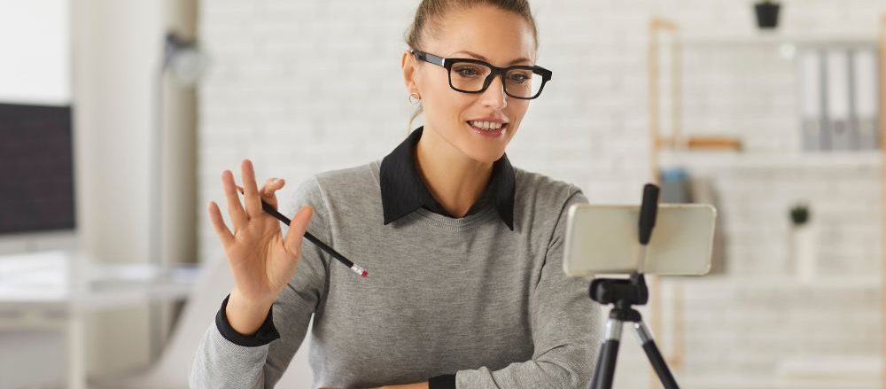 A woman delivering a lecture to a webcam.