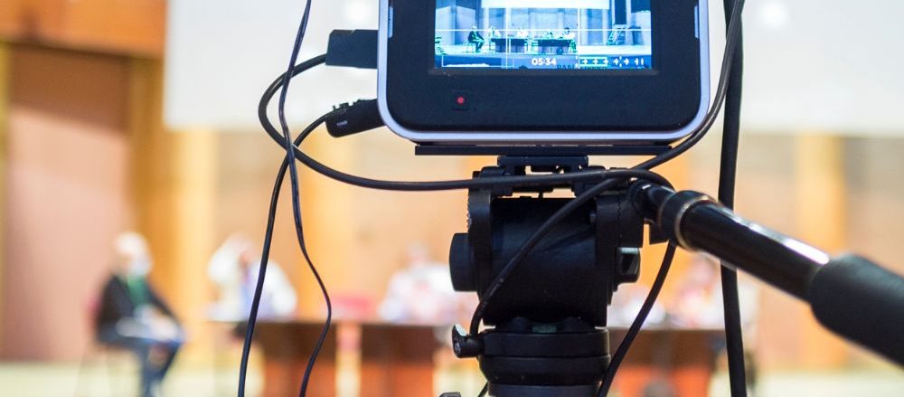 A video camera live streams an in-person event session.